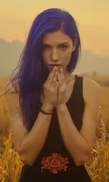 a girl standing in the middle of a field with her hands to her face