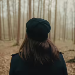 woman in black standing alone in a forest