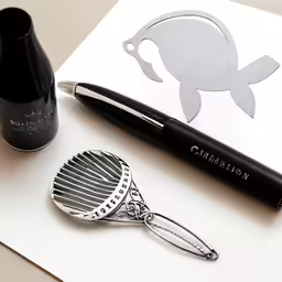 a fountain pen sitting next to a brush and a cup
