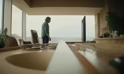 a man standing at a kitchen sink in front of a window
