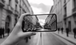 a person holding up their cell phone taking a photo of the street