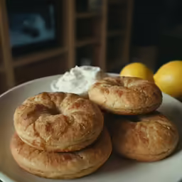 several bagels on a plate with some whipped cream