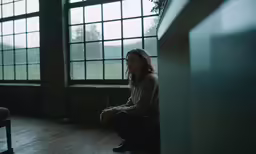 a woman sitting on the floor looking out the window