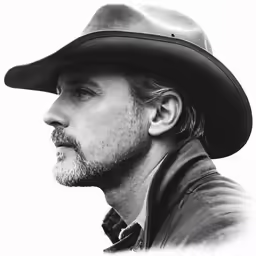 a close up view of a cowboy, with his hat down and a beard in the middle of his face