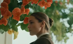 a beautiful young lady standing in front of some orange flowers