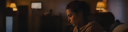 a woman stares into the distance, in an otherwise dark room