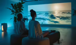 two women are sitting on bean bags looking at an image on the wall