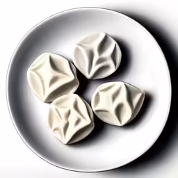 three cream cookies that look like leaves on a white plate