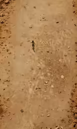 the top view of a dirt and rock hill with a lone person walking in it
