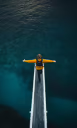 an overhead view of a man standing on a pier over the ocean