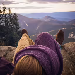 person with purple sweater and hat looking over mountains