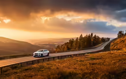 a white car driving on a highway near mountains