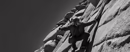 two people climbing up the side of a rock wall