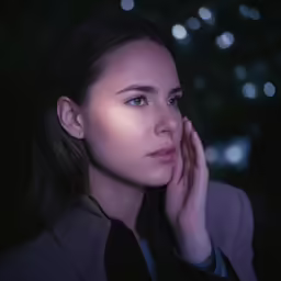 a woman looking into the distance holding her hand near her face