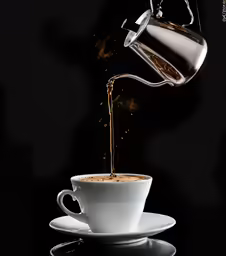 white coffee cup filled with black liquid being poured into it