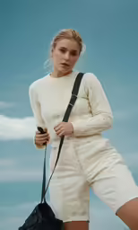 a woman holding a handbag and wearing white clothing