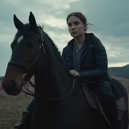 a woman is sitting on a black horse in the mountains