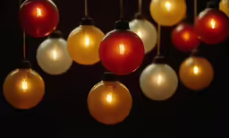 colorful, lit balls and bulbs hang in a dark room