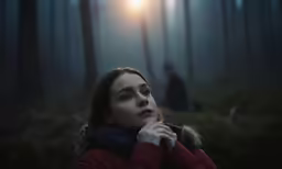 a young woman with her eyes closed, staring out into the distance, in a forest