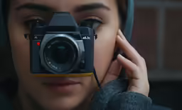 a woman with a camera and hooded jacket holding the same camera