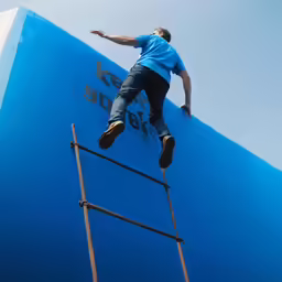 man climbing up and down a ladder to reach the top