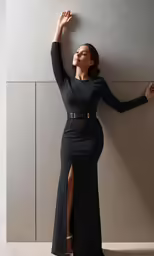 the model wears a black gown with a high slit and slited knee - high boots