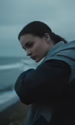 a woman in grey hoodie on an overcast beach