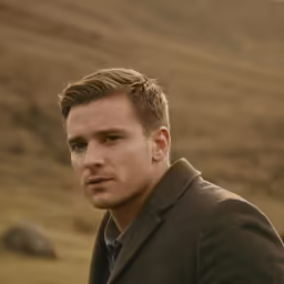 a man in the field with a green jacket and his eyes closed