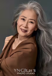 an old asian woman with grey hair smiling,an older woman in a brown sweater is smiling