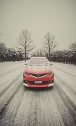 red car driving on snowy road near trees