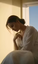there is a woman that is sitting down and holding her hand to her head