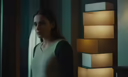 a woman standing in a room with two lamps behind her
