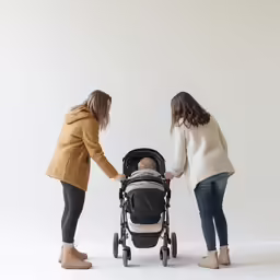 two females pushing strollers one with baby in the back