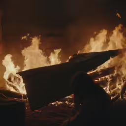 the back side of a person standing in front of a fire