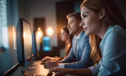 three people are looking at the screen of a laptop