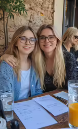 two young women smiling while sitting at a restaurant