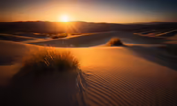 the sun sets behind a mountain and dunes