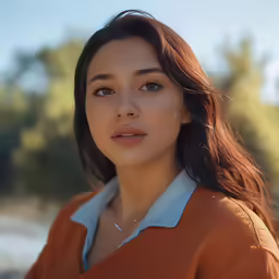 this girl is looking at the camera while she has brown hair and blue eyes