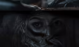 a scary looking woman making a face, with her hand to her mouth