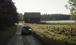 a car is parked on a road near a red house