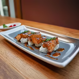 salmon and rice on a silver plate with sauce on top