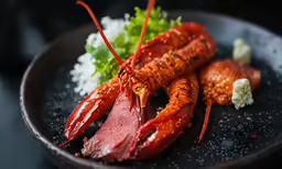a close up of lobster on a plate with greens