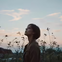 a woman looking up at some flowers in a field