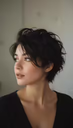 a woman with very short dark hair is looking away
