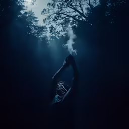 a person holding their hands up above their head in the dark