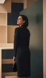 a woman in a black dress holding a handbag looking at something