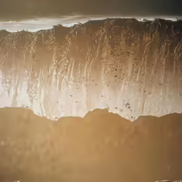 a very large wave hitting the shore at dusk
