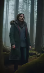 woman in hooded parka looking at camera in forest