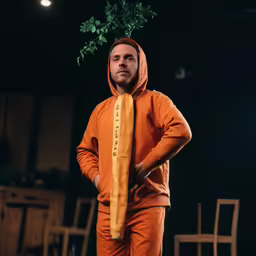 a person in orange is standing with his hands on his hips
