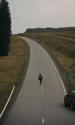 a lone man walking down the middle of the road